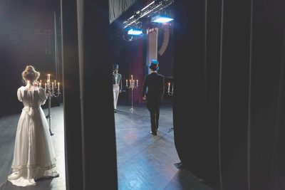 Les coulisses : le portant à costumes, et la porte ouverte sur le plateau éclairé.