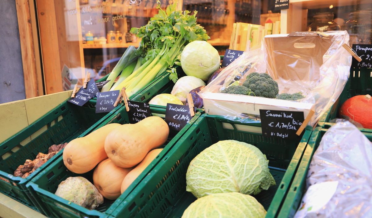 Le local de l’épicerie : les cagettes de légumes sur la table, le rideau métallique relevé.