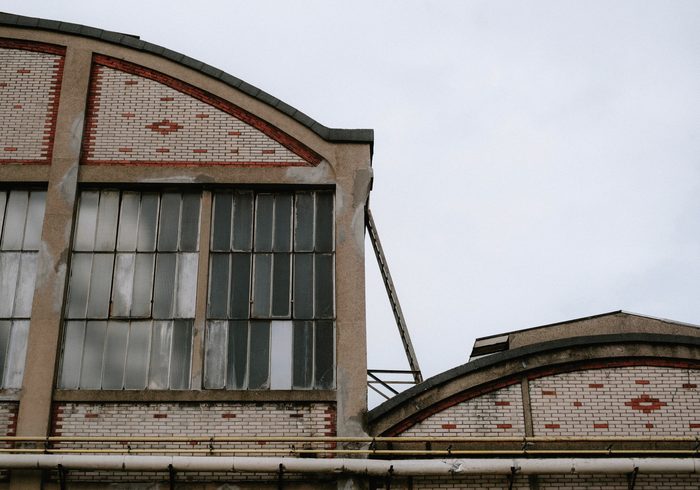 La façade de la halle : le volume plein et la façade vitrée, le parvis devant.