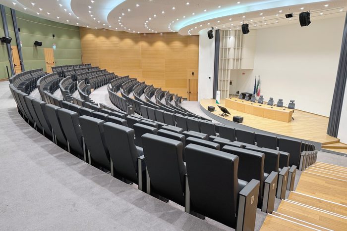 L’auditorium : l’écran allumé, la table des intervenants, le public de dos.